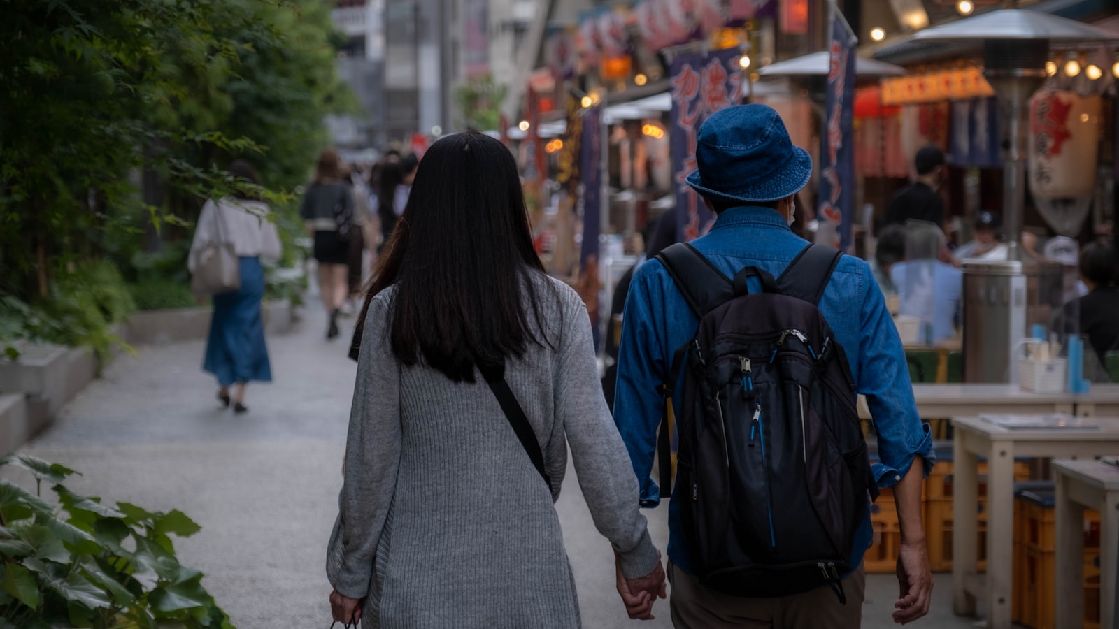 A couple walking hand in hand down a lantern-lit street